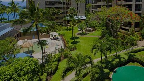 A hotel with multiple floors, outdoor swimming pool, palm trees, and a view of the ocean.