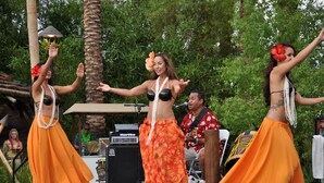 A stage with performers in orange skirts and black bras, a microphone stand, and musical equipment.
