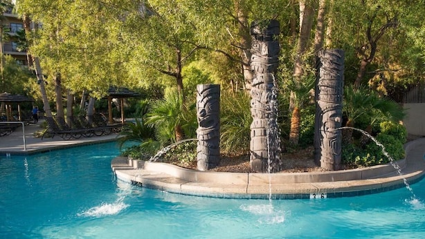 A swimming pool with a central island featuring stone sculptures and a water feature.