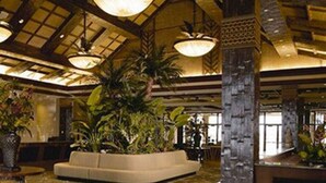 A lobby with a high ceiling, large chandeliers, a sofa, and potted plants.