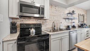 Una cocina moderna con electrodomésticos de acero inoxidable, armarios blancos y un protector contra salpicaduras de madera.