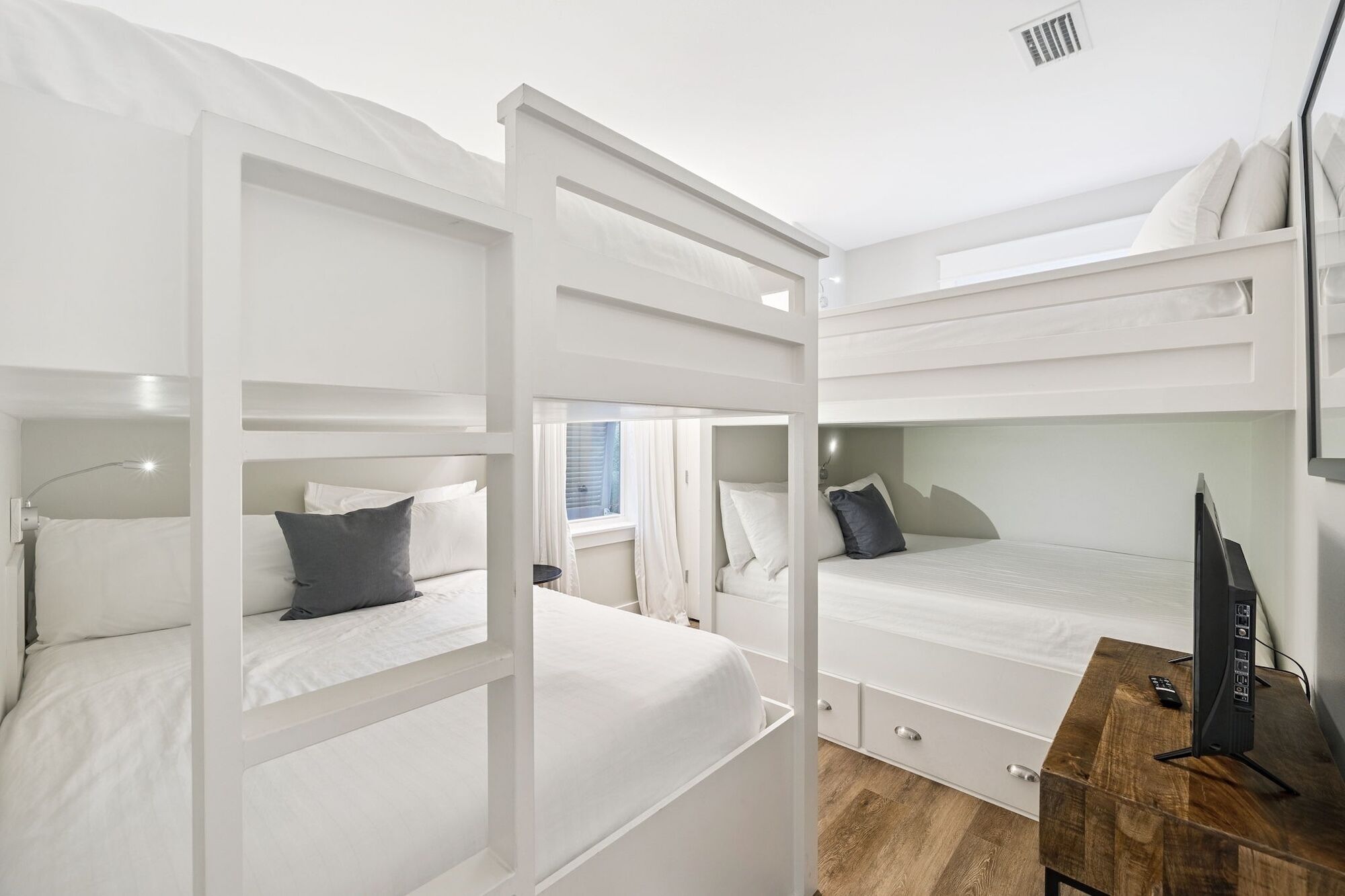 Une chambre avec un lit superposé, un bureau en bois et un téléviseur.