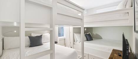 Une chambre avec un lit superposé, un bureau en bois et un téléviseur.
