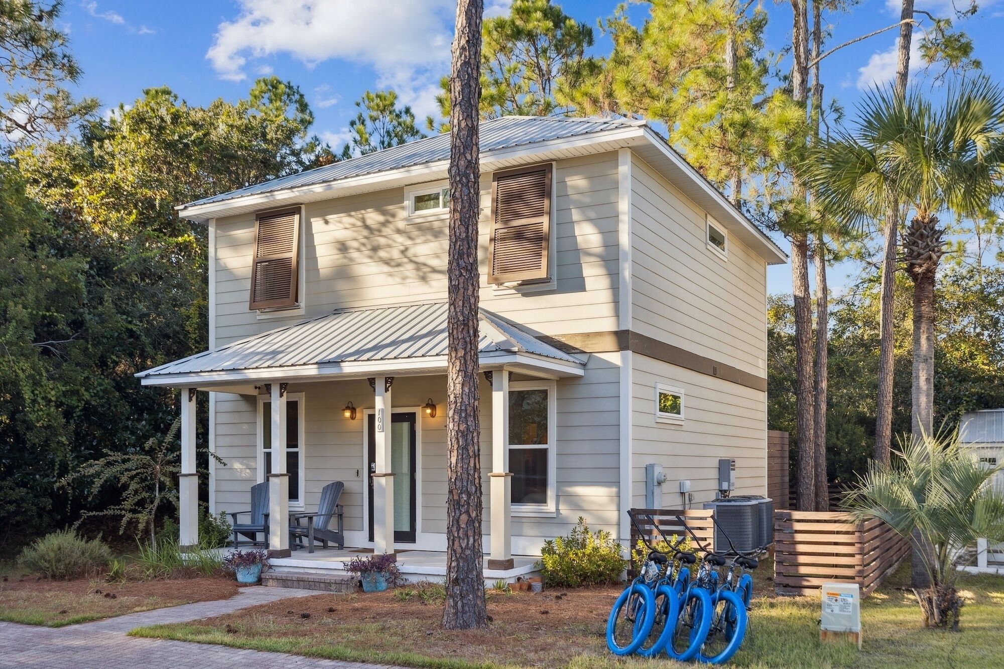 A two-story house with a porch, a covered patio, and a small garden area.