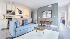 A modern living room with a sofa, coffee table, and a dining area with chairs. - Milk153-6G-1/1 · Bright FIDI 1br | Centrally Located (Boston)