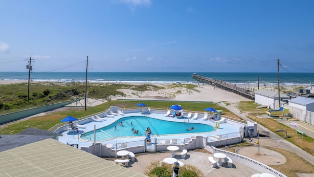 A swimming pool with a beach view, surrounded by lounge chairs and umbrellas. - Oceanana Motel (Atlantic Beach)
