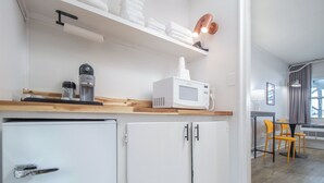 A compact kitchen with a microwave, coffee machine, and a small refrigerator. There is a dining area with a table and chairs. - Oceanana Motel (Atlantic Beach)