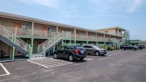 A motel with multiple rooms, a parking lot, and a staircase leading to the entrance. - Oceanana Motel (Atlantic Beach)