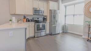 A modern kitchen with white cabinets, stainless steel appliances, and a large window providing natural light. - Luxurious 1BR in FIDI Boston | Close to Everything (Boston)