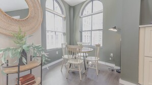 A dining area with a round table and chairs, a large mirror, and a potted plant. - Luxurious 1BR in FIDI Boston | Close to Everything (Boston)