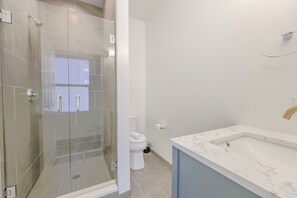 A modern bathroom with a glass-enclosed shower, a white toilet, and a marble sink. - Luxury Loft | W/D in Unit | Pet Friendly (Boston)