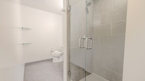 Une salle de bain moderne avec une douche à parois de verre, des toilettes et une étagère en verre.
