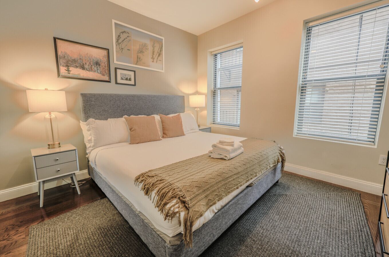 A neatly arranged bedroom with a large bed, two bedside tables, and a window with blinds.