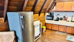 Une cuisine compacte avec des meubles en bois, un réfrigérateur en acier inoxydable, un four à micro-ondes et une machine à café.
