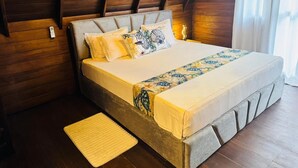 Une chambre avec un plafond en bois, un lit avec une literie à motifs et une table de chevet.