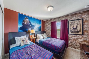 Ein Hotelzimmer mit zwei Betten, einer Steinwand, einem Poster eines Zauberers und einem gerahmten Bild, das fragt, ob der Betrachter diesen Zauberer gesehen hat.