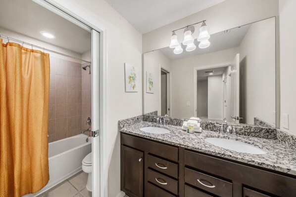 Une salle de bain avec deux lavabos, une douche et des toilettes.