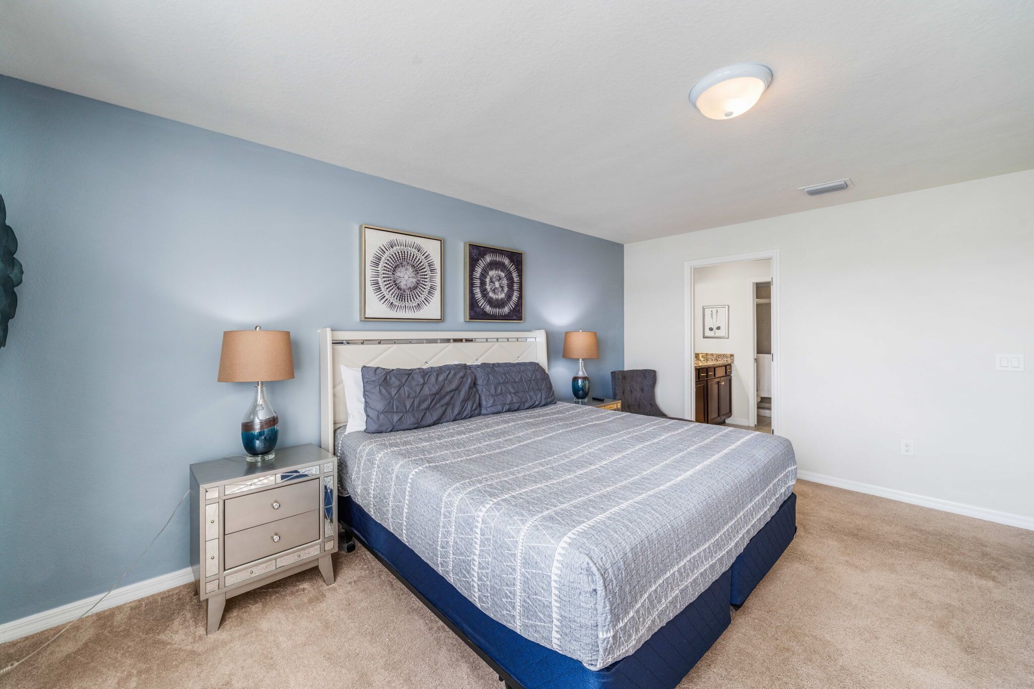 A bedroom with a bed, nightstands, and wall art.