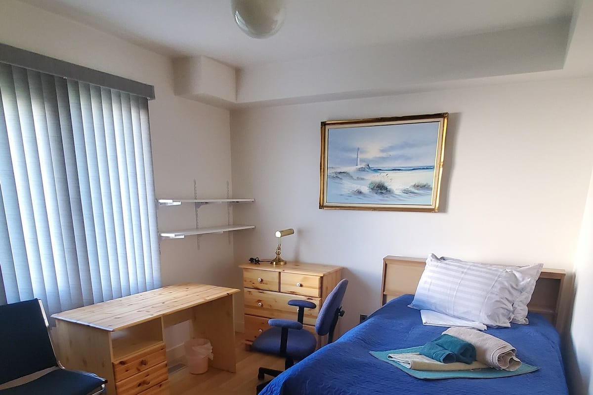 Une chambre à coucher avec un lit, un bureau, une chaise et un tableau accroché au mur.