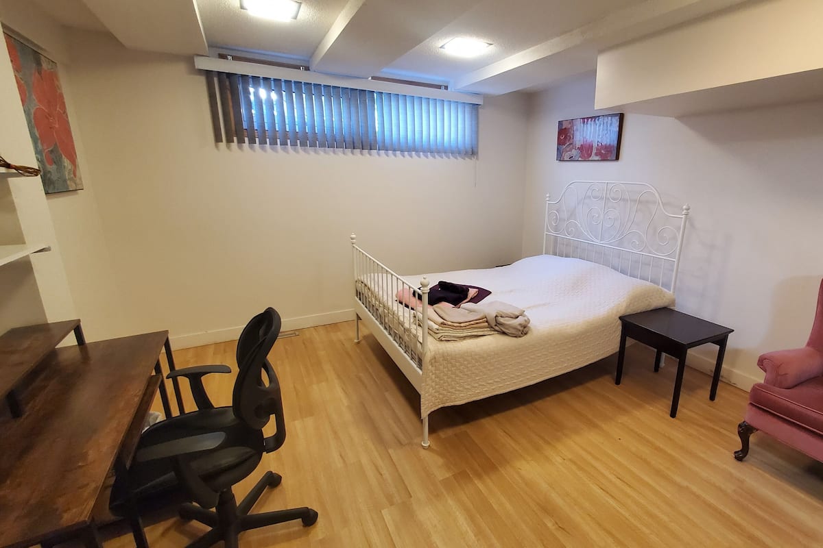 Une chambre avec un lit simple, un bureau, une chaise et une petite table.