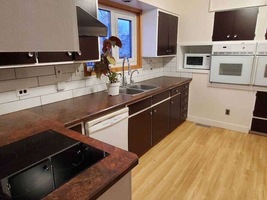 Et moderne køkken med en central ø, indbyggede hårde hvidevarer og et vindue.