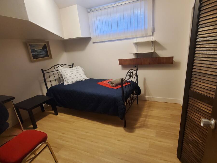 Ein kleines, helles Schlafzimmer mit Bett, Schreibtisch und Stuhl.