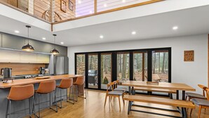 A modern kitchen with a wooden island, bar stools, and a dining area with benches. - Superb 6-bedroom house with HVAC in charming Pocono Pines (Pocono Pines)