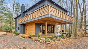 A modern two-story house with a wooden deck, large windows, and a stone foundation. - Superb 6-bedroom house with HVAC in charming Pocono Pines (Pocono Pines)