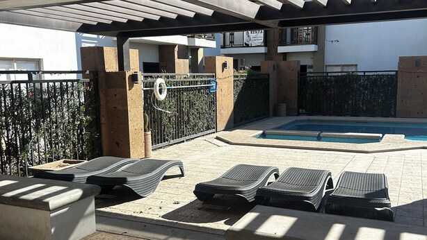 A covered outdoor area with a pool, lounge chairs, and a pergola. - SPACIOUS CONDOMINIUM, CLOSE TO AIRPORT (Hermosillo)