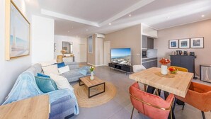 Una sala de estar moderna con un sofá, una mesa de centro, televisor y comedor.