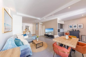 A modern living room with a sofa, coffee table, TV, and dining area. - SoNice · Modern, 2 BR, 2 Bath, TOP location, 2 balc (Nice)