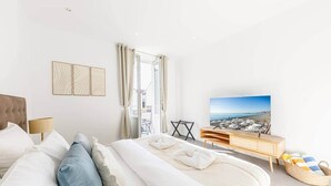 Un dormitorio moderno con cama, televisión y vista a la playa.