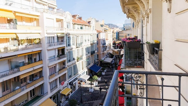Un edificio de varios pisos con balcones, una calle abajo y cielo despejado.