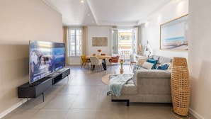 Una sala moderna con televisor de pantalla plana, un sofá, un comedor y un amplio ventanal.
