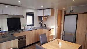Una cocina moderna con armarios de madera, un lavamanos de acero inoxidable, un microondas y un refrigerador.