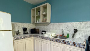 Eine Küche mit weißen Schränken, einer gefliesten Spritzschutzwand und einer blauen Wand.