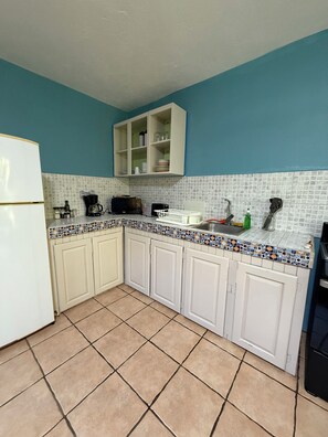 A kitchen with white cabinets, a tiled backsplash, and a blue wall. - #1 Cozy 1-bedroom apartment in Cahuita with AC, Parking- near nat'l park, beach (Cahuita)