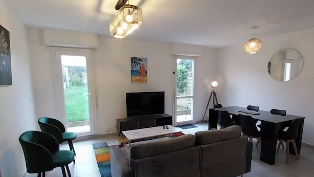 Uma sala de estar moderna com sofá, TV, mesa de jantar e cadeiras.