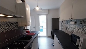 Cozinha moderna com fogão a gás, forno e micro-ondas. Há uma janela com vista para o exterior.