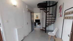 Um interior moderno com uma escada em espiral, uma cadeira branca e um banco.