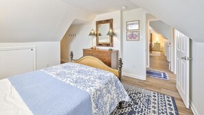 A bedroom with a bed, dresser, mirror, and a hallway leading to a staircase. - Great for Families! Short Drive to Beaches! (Cape May)