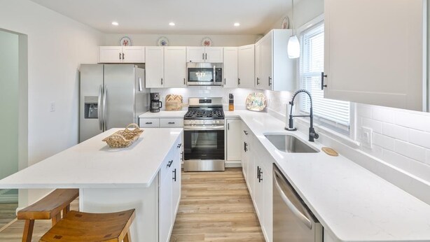 A modern kitchen with white cabinetry, stainless steel appliances, and a wooden bench. - Great for Families! Short Drive to Beaches! (Cape May)