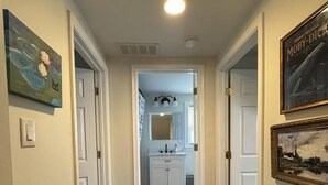 A hallway leading to a bathroom with a white vanity and a mirror. - Great for Families! Short Drive to Beaches! (Cape May)