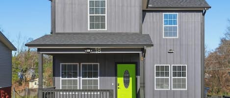 A two-story house with a front porch, a green door, and a number '18' on the front.
