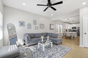 A modern living room with a grey sectional sofa, a glass coffee table, and a patterned rug. - 4 Bedroom House Perfect for Large Groups Sleeps 10 (Greenville)