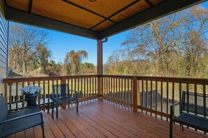 Una terraza techada al aire libre con barandillas de madera, una mesa con sillas y una planta en maceta.