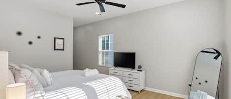 A bedroom with a bed, a dresser, a television, a ceiling fan, and a mirror.
