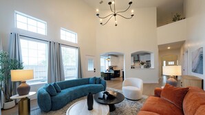 Una sala de estar amplia con un sofá modular, una mesa de centro redonda y un candelabro.