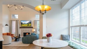 Una sala de estar con chimenea, sofá, televisor y un comedor con mesa y sillas.