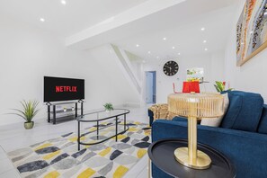 A modern living room with a flat-screen TV, a sofa, a coffee table, and a staircase. - Charming 3Bed 2Bath in Windsor /Near Heathrow - Free Parking (Windsor)